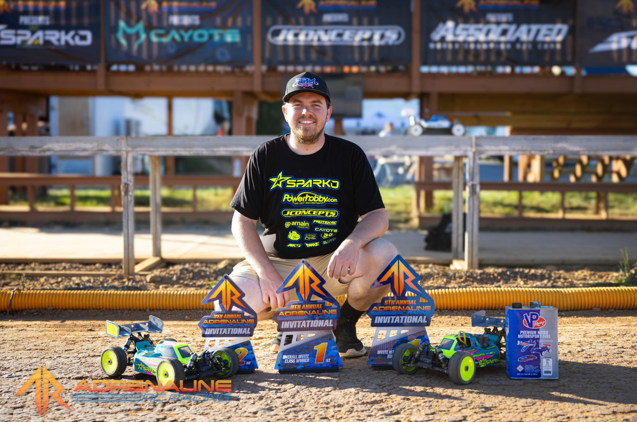 Lee Setser posing with Sparko RC cars and branded trophies at a adrenaline rc invitational racing event